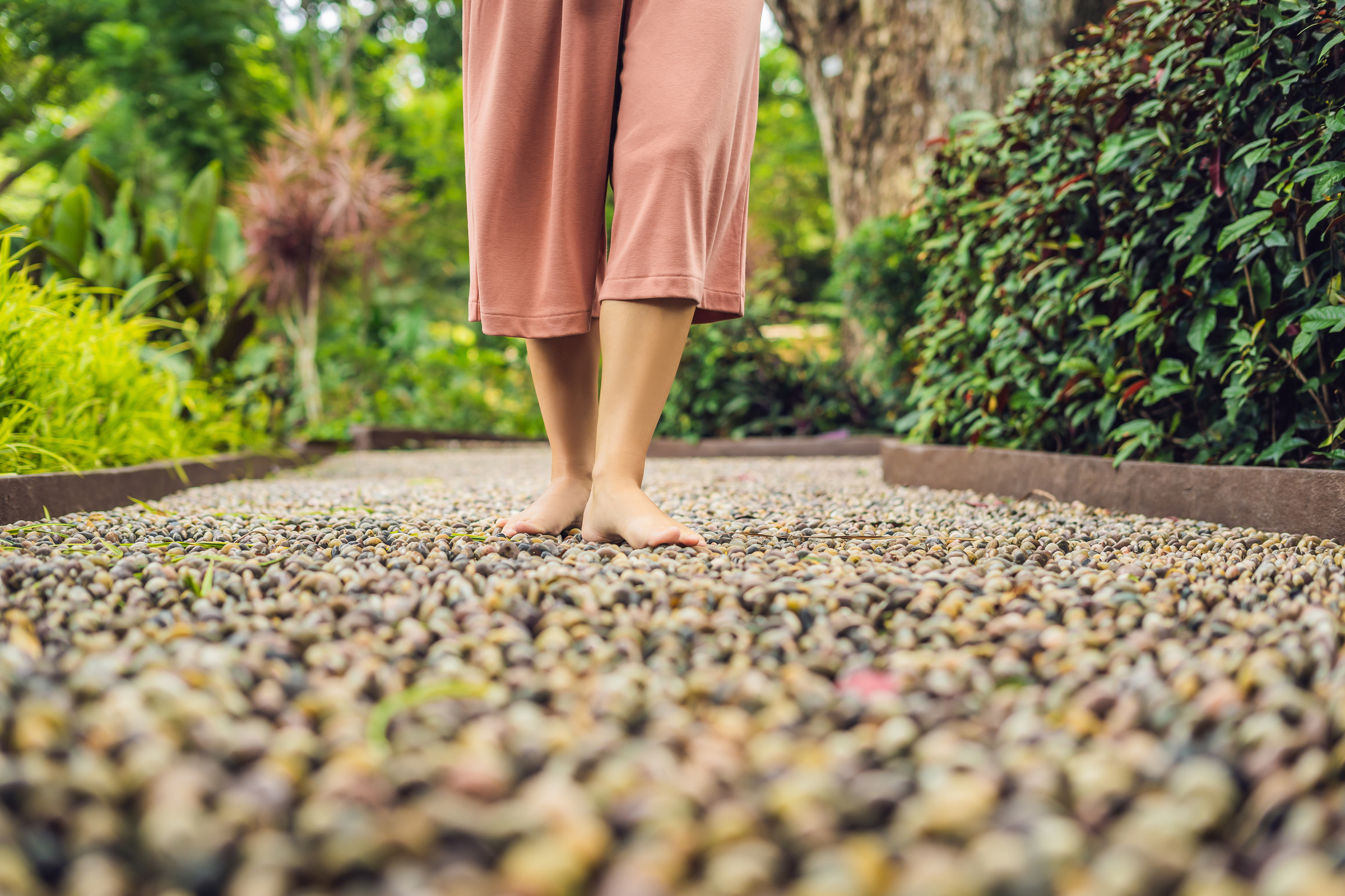 Woman Walking on a Textured Cobble Pavement, Reflexology. Pebble Stones on the Pavement for Foot Reflexology